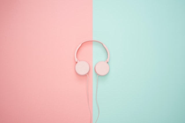 Pink wired headphones on a pink-turquoise wall