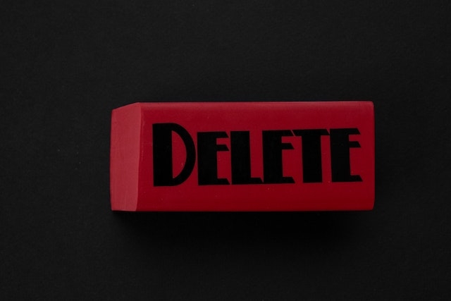 Roter Radiergummi auf schwarzem Hintergrund mit dem Wort Delete